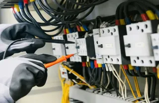 Photo by Toolmash Expo — electrician testing an electrical panel with a multimeter