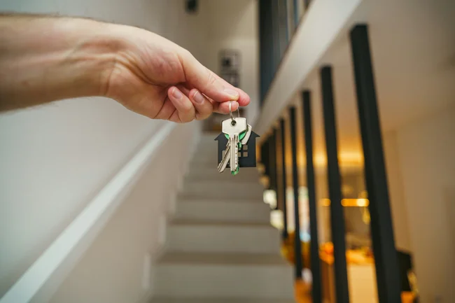 First home buyers holding house keys in front of their new home